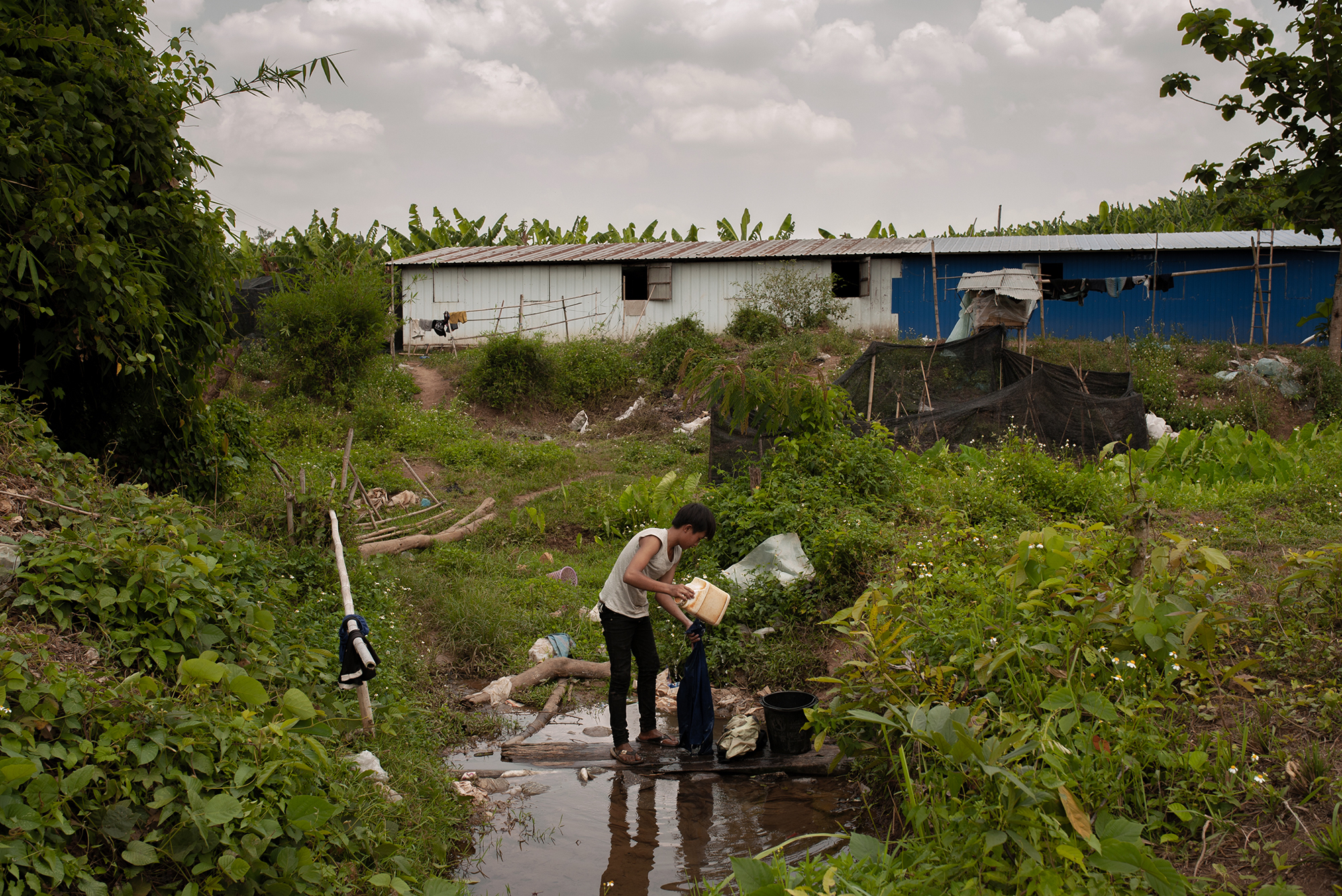 Ton washes his clothes in a small creek below the plantation (Image: Visarut Sankham/China Dialogue)