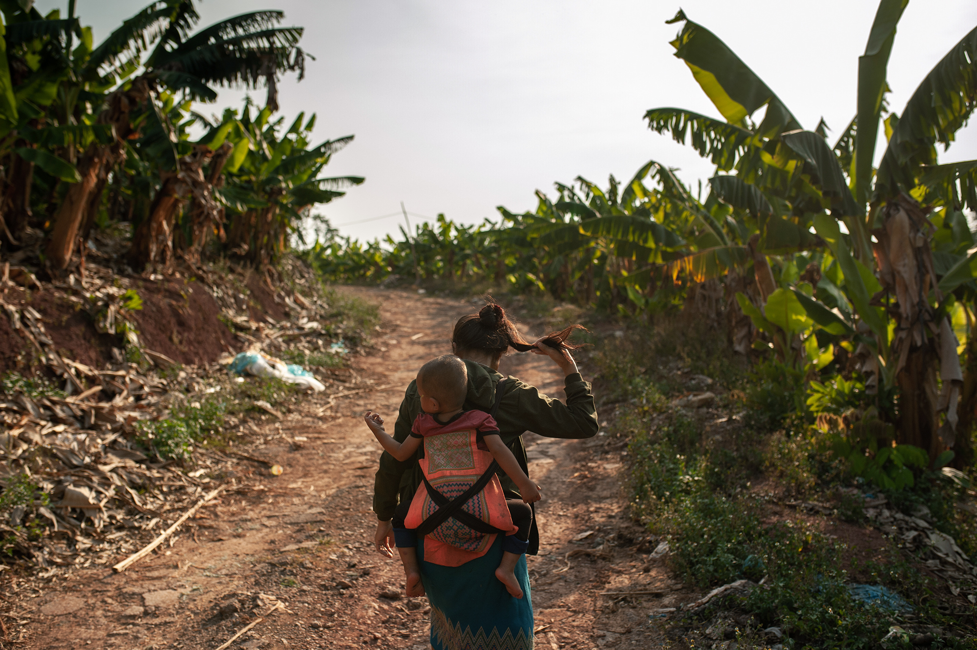 Mohin, 28, and her child on their way to the plantation; workers usually work every day from 7:30 am to 6:30 pm. (Image: Visarut Sankham/China Dialogue)