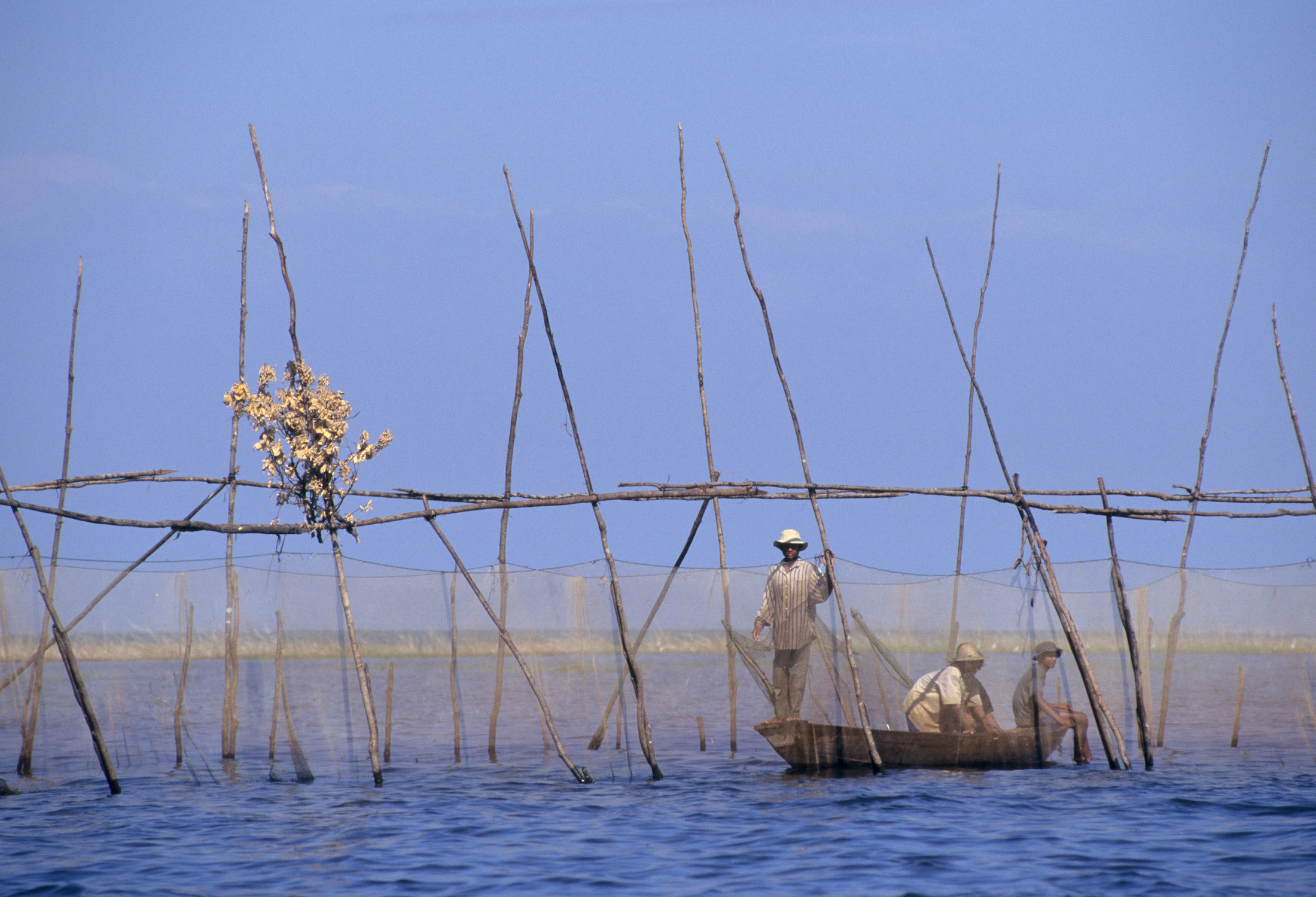 three men in a boat fishing on Tonle sap lake